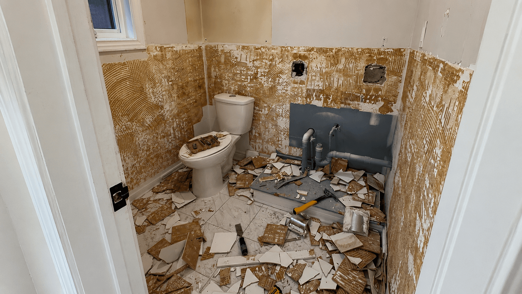 Bathroom before renovation with exposed wall preparation, unfinished shower area, and construction materials