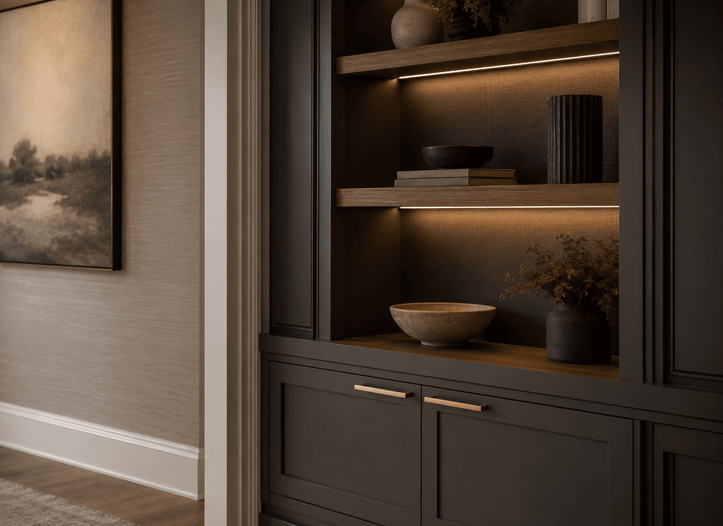 Dark custom shelving detail with warm integrated lighting, wood shelves, charcoal cabinetry, and brass hardware
