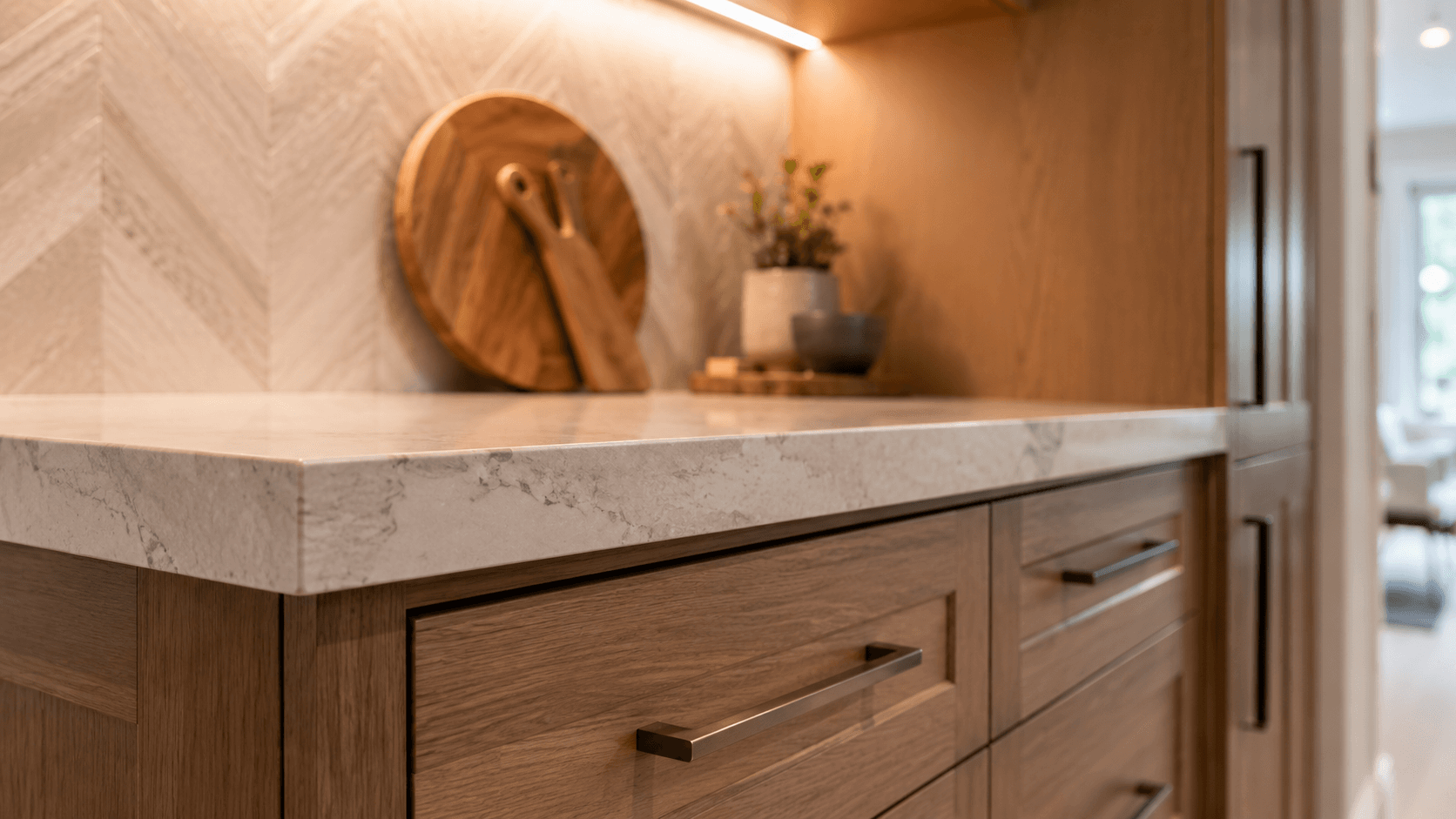 Close-up of kitchen stone countertop, oak cabinetry, and warm under-cabinet lighting